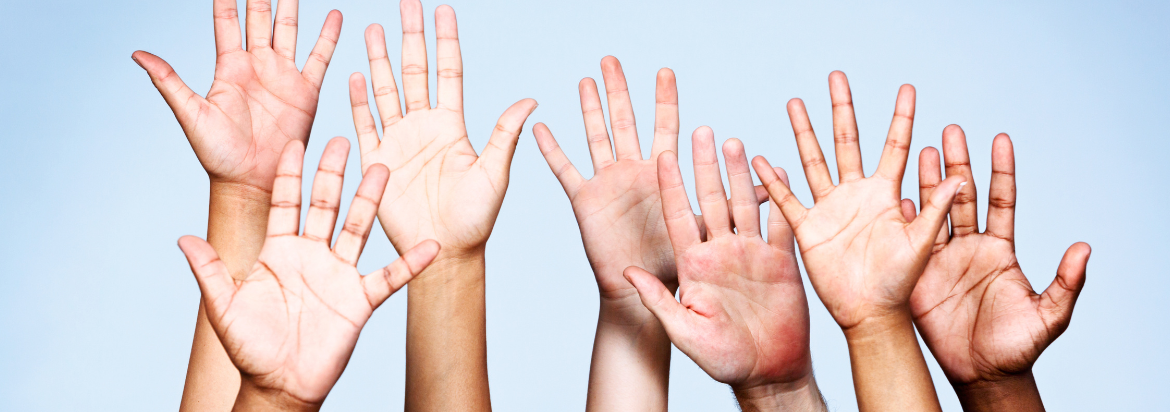 a group of hands raised with the sky in the background