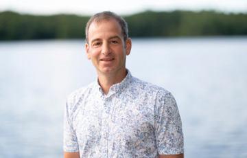 Dr. Paul Winston standing in front of a lake with trees in the background